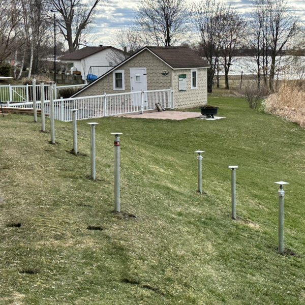 Screw piles installed in a backyard with the lawn intact, ready for construction